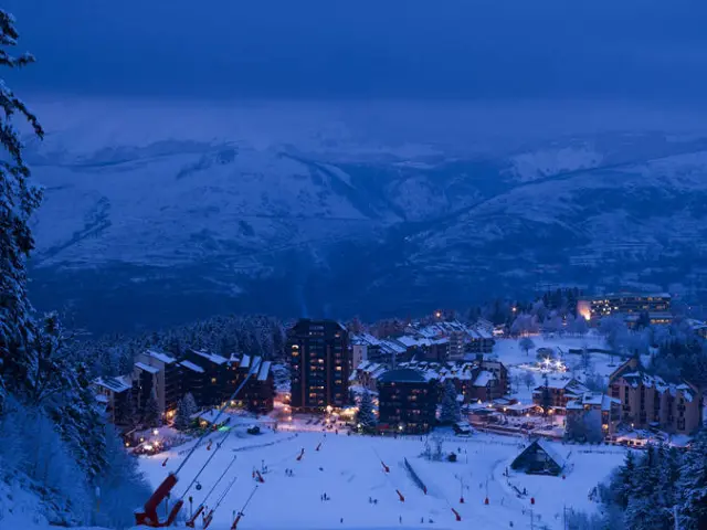 Vue d'une station de ski enneigée avec des pistes éclairées et des bâtiments