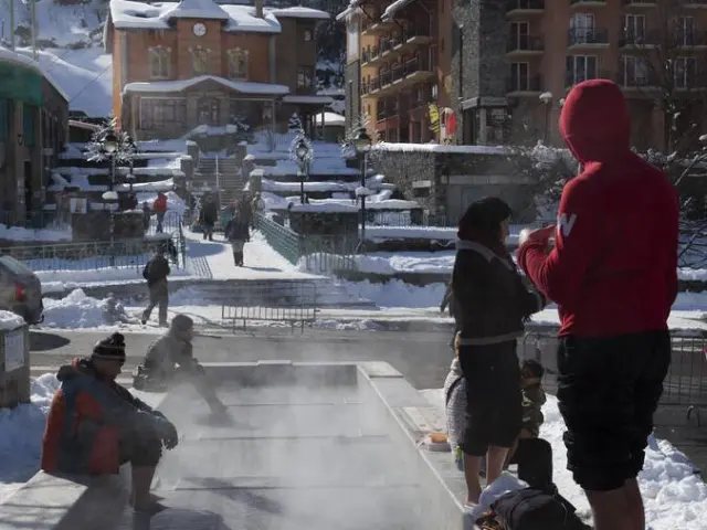 Personnes profitant d'une source chaude en plein air dans un village de montagne enneigé
