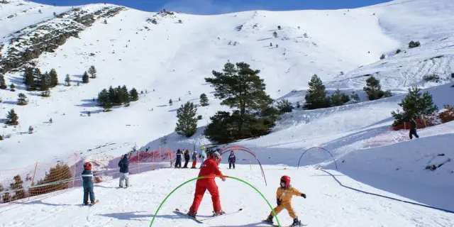 Enfants faisant du ski avec des instructeurs sur une piste enneigée