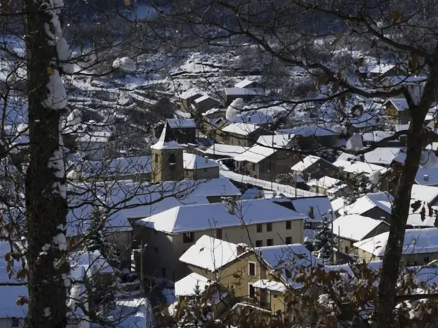 Pueblo cubierto de nieve con techos nevados y árboles desnudos