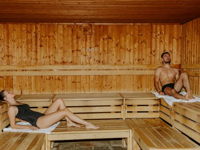 Dos personas relajándose en una sauna de madera