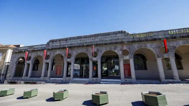 Edificio histórico con columnas y arcos, decorado con banderas rojas