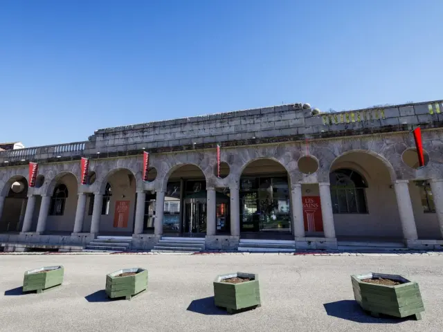 Edificio histórico con columnas y arcos, decorado con banderas rojas