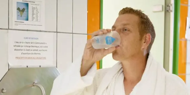 Homme en robe de bain buvant de l'eau à une fontaine