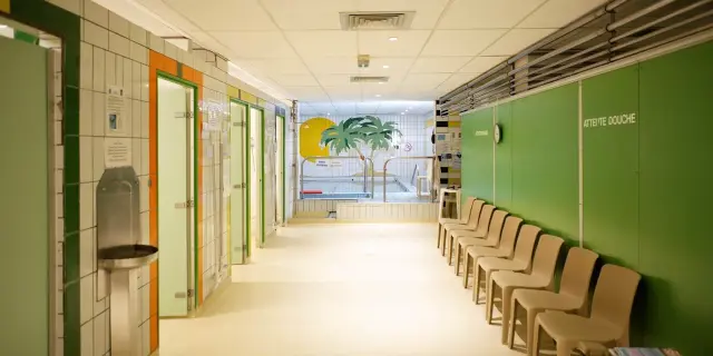 Salle d'attente avec des chaises alignées et des cabines vertes