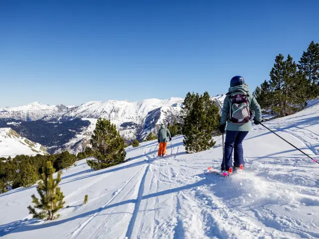 Dos personas haciendo esquí de travesía en un paisaje nevado