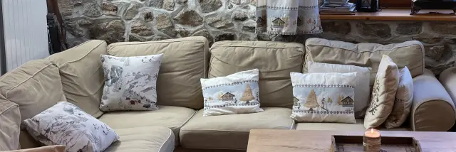 Salon avec canapé beige, coussins décoratifs et cheminée en pierre