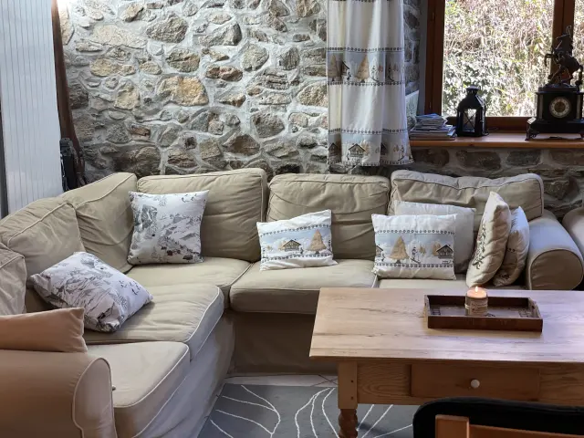 Salon avec canapé beige, coussins décoratifs et cheminée en pierre