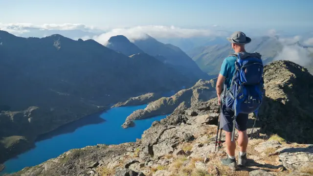 Un randonneur avec un sac à dos sur un sentier de montagne avec vue sur un lac