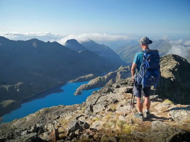Un randonneur avec un sac à dos sur un sentier de montagne avec vue sur un lac
