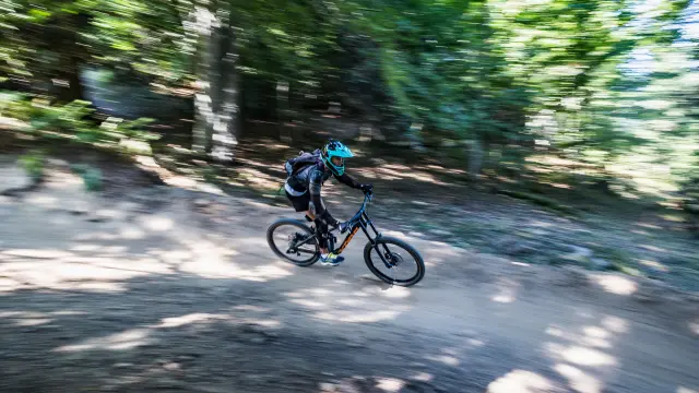 Un cycliste en tenue de protection pédale rapidement sur un sentier forestier