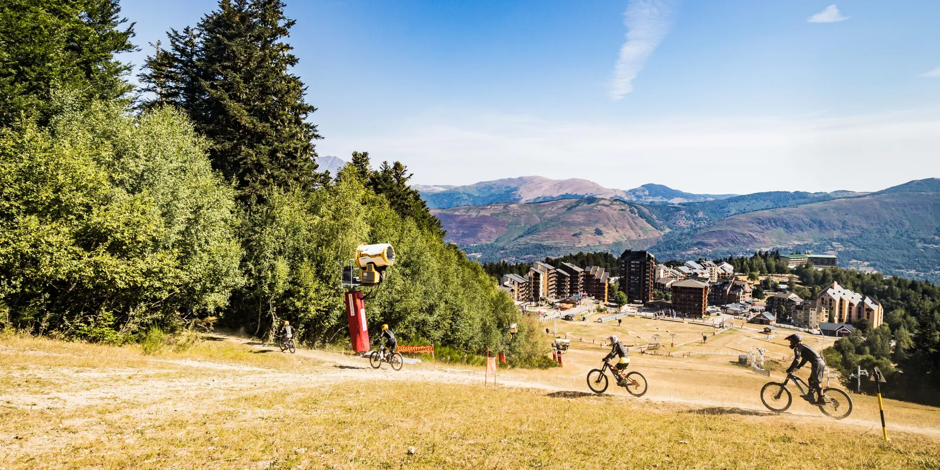Trois cyclistes sur un sentier de montagne avec vue sur un village