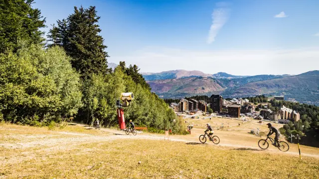 Trois cyclistes sur un sentier de montagne avec vue sur un village