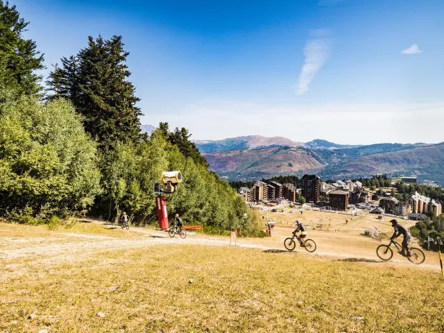 Trois cyclistes sur un sentier de montagne avec vue sur un village