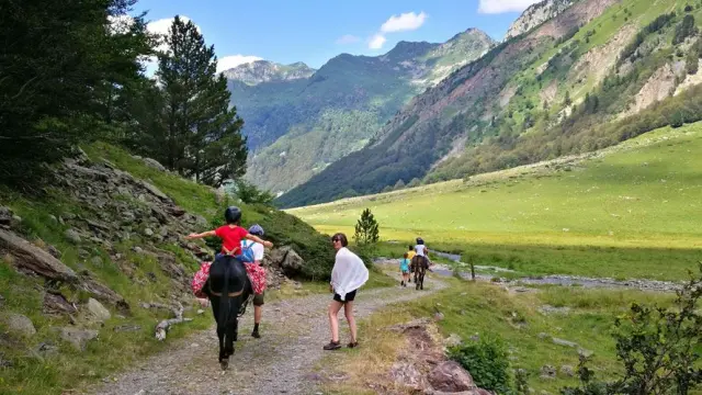 Groupe de personnes en randonnée équestre dans une vallée montagneuse