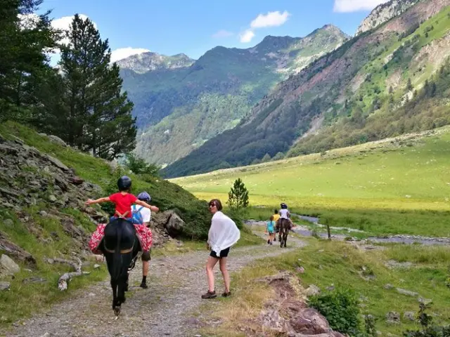 Groupe de personnes en randonnée équestre dans une vallée montagneuse