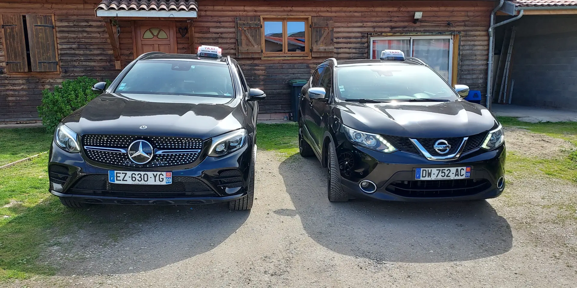 Deux voitures noires garées devant une maison en bois