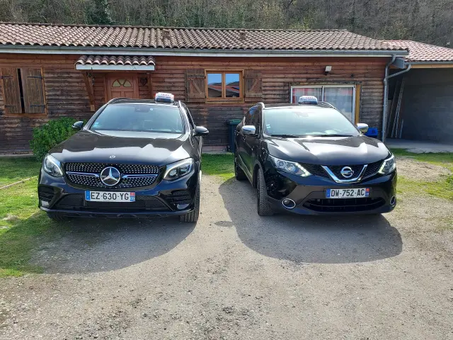 Deux voitures noires garées devant une maison en bois