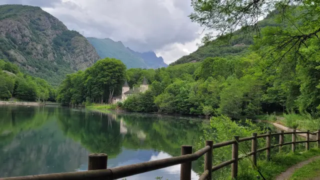 A serene lake surrounded by greenery with mountains in the background