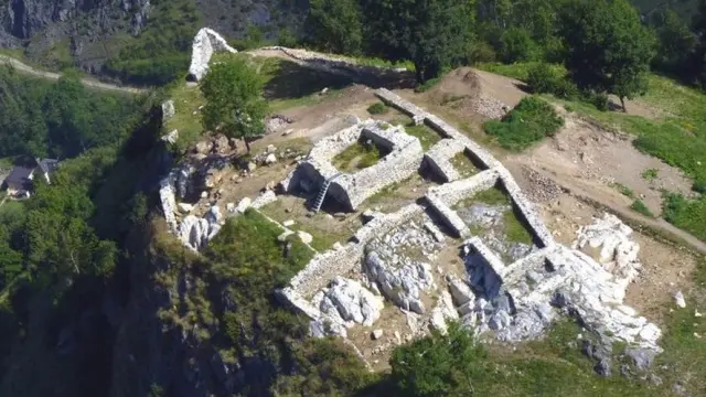 Ruines de pierre sur une colline avec une vue sur une rivière