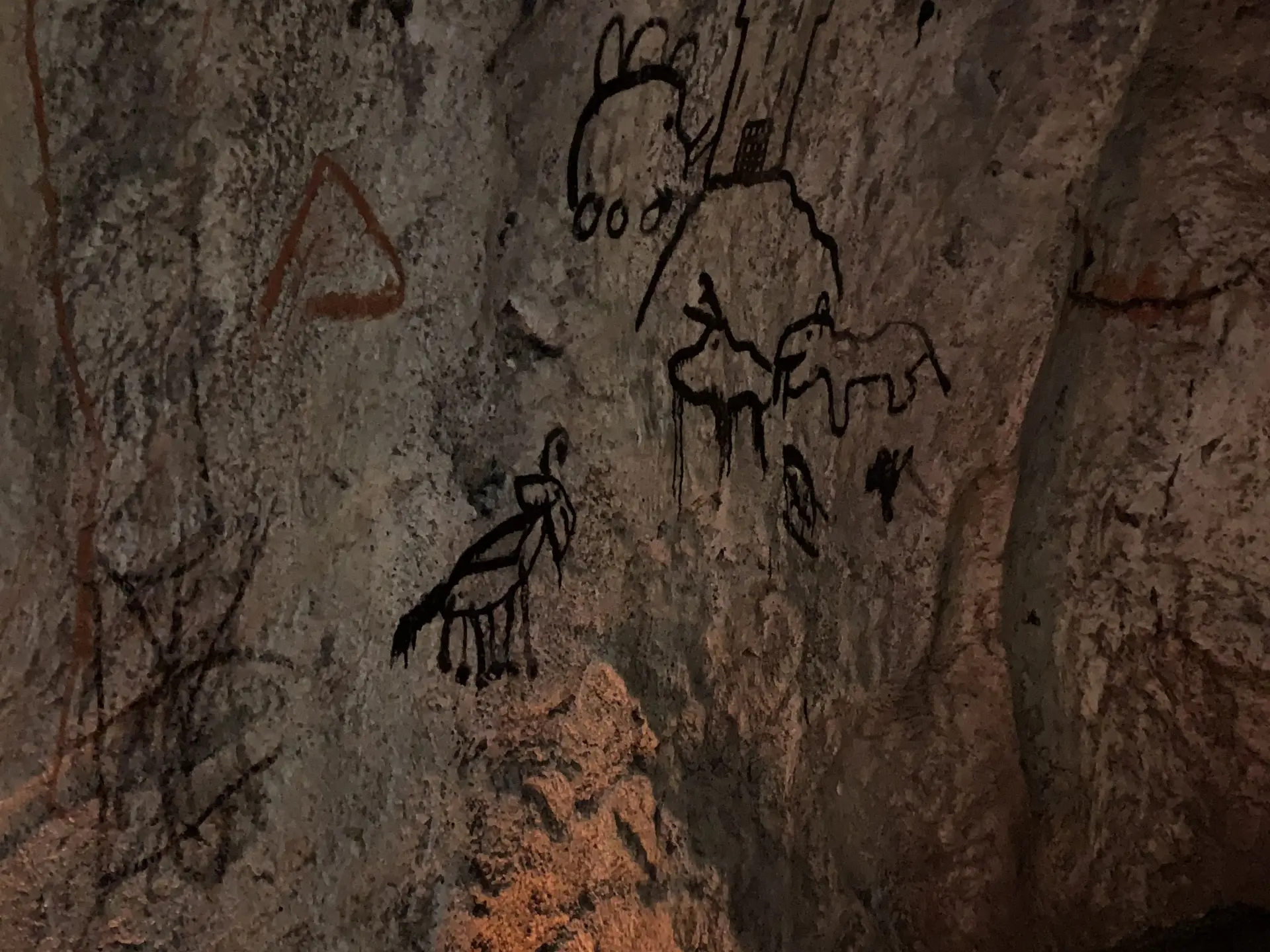 Stone wall with ancient rock carvings depicting human and animal figures
