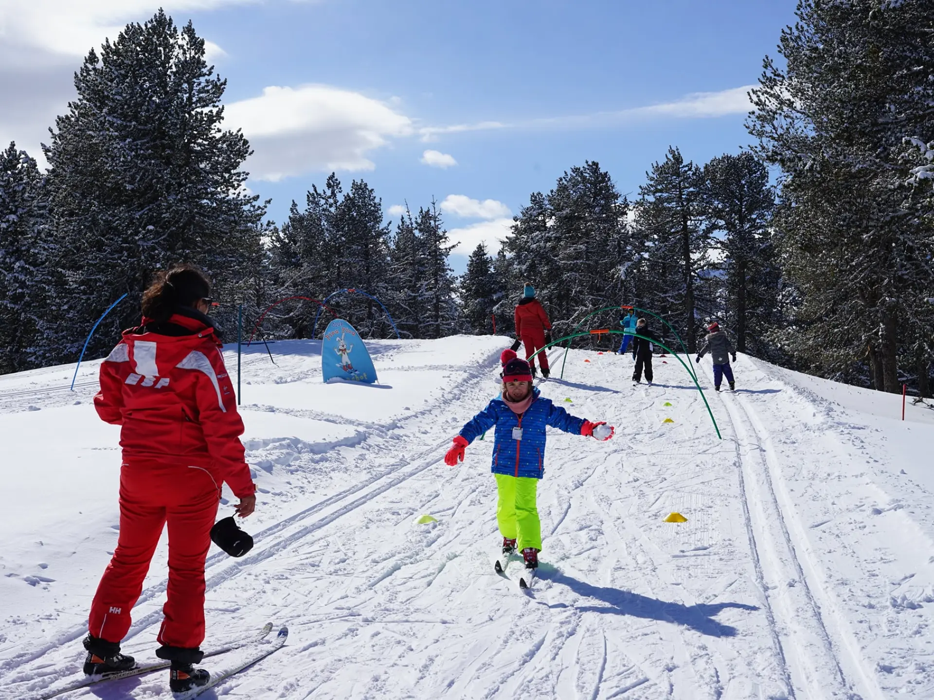 Child skiing with an instructor in a snowy landscape
