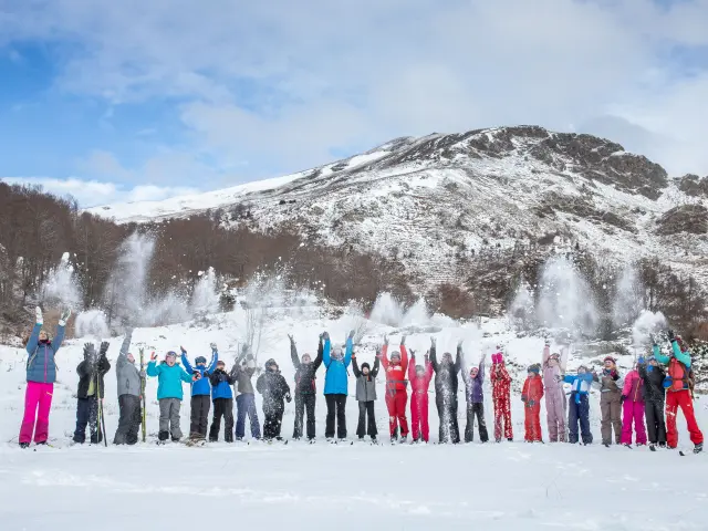 Un groupe de personnes en tenue de ski posant devant une montagne enneigée