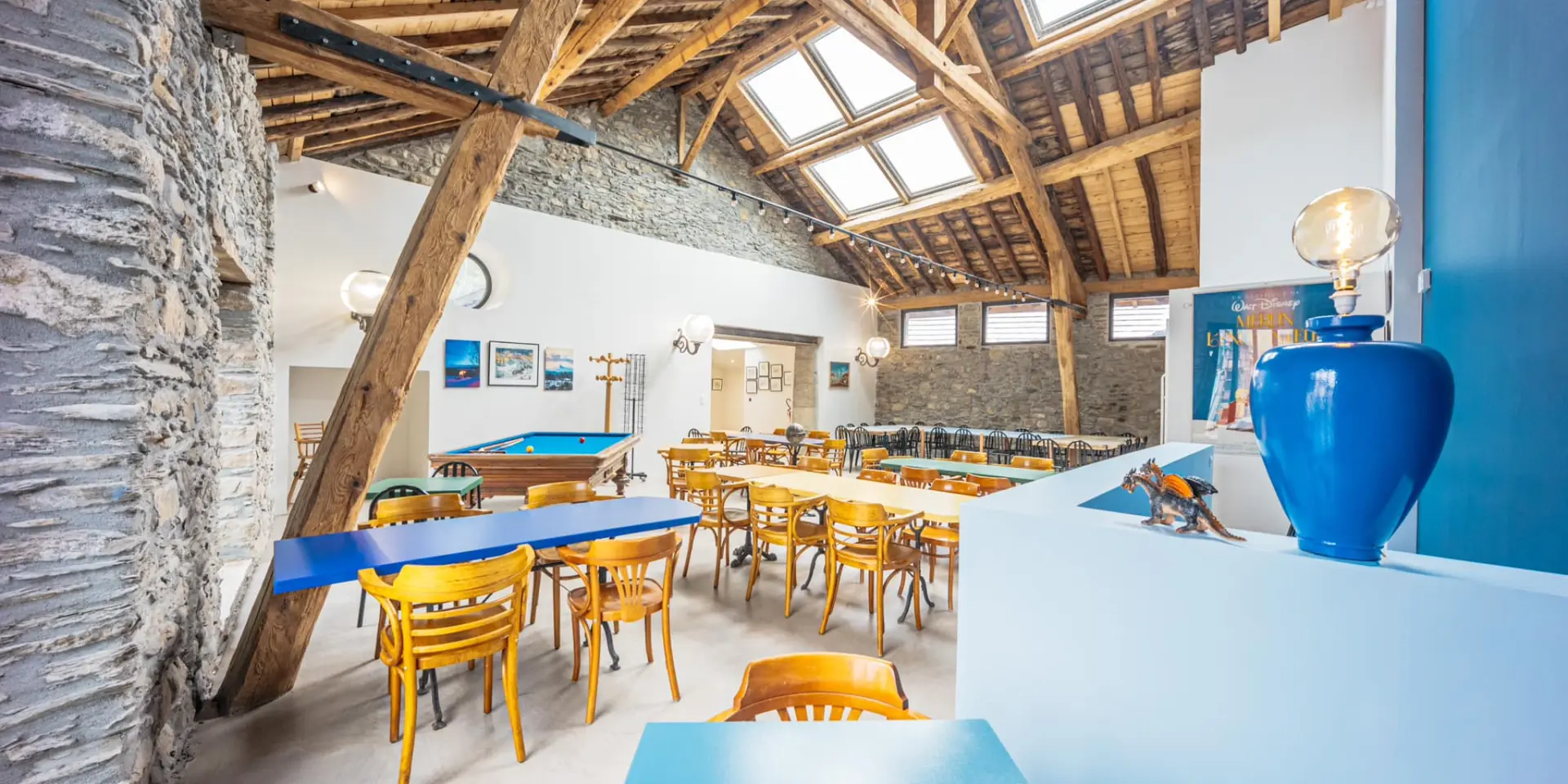 Dining room with wooden tables and chairs, stone walls and exposed beams