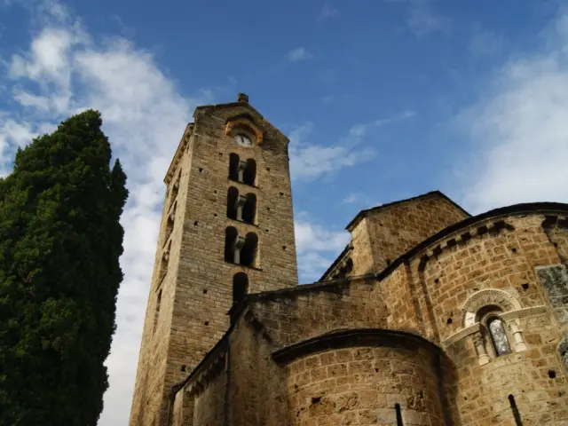 Église médiévale en pierre avec un clocher et un arbre à gauche