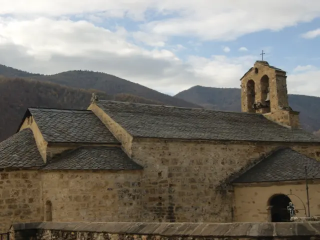 Église en pierre avec un clocher, située dans une vallée montagneuse