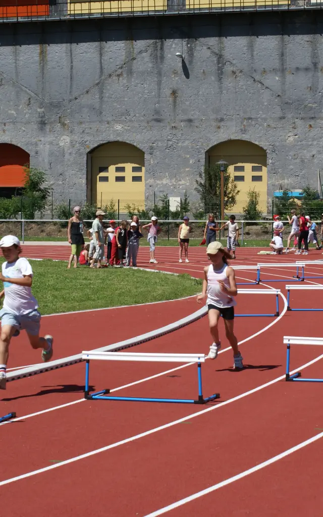 Enfants courant sur une piste d'athlétisme avec des haies