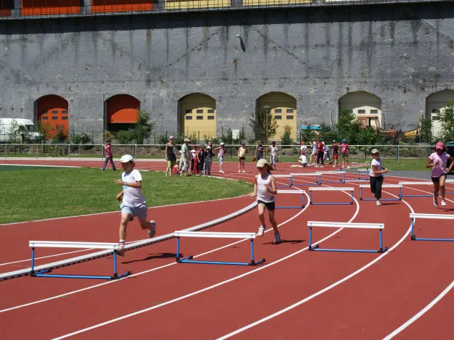 Enfants courant sur une piste d'athlétisme avec des haies