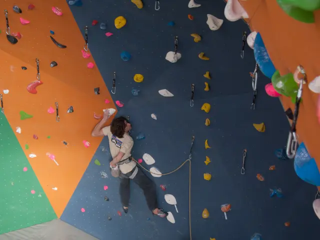 Personne en train d’escalader un mur coloré en salle d’escalade