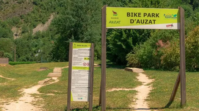 Panneau d'entrée du Bike Park d'Auzat avec des pistes cyclables en arrière-plan