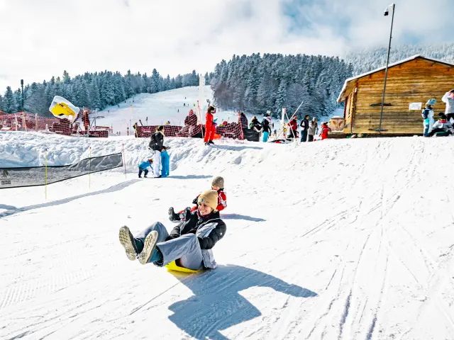 Enfants descendant une pente enneigée avec des luges
