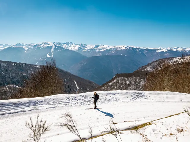 Person walking in the snow with mountains in the background