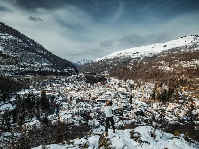 Person standing on a snowy hill with a village below