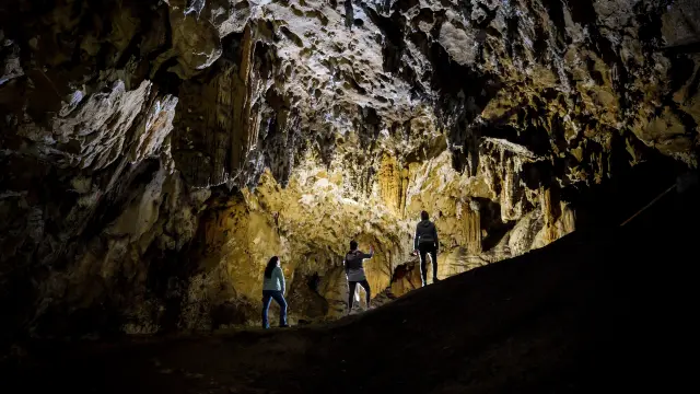 Tres personas explorando una cueva con formaciones rocosas