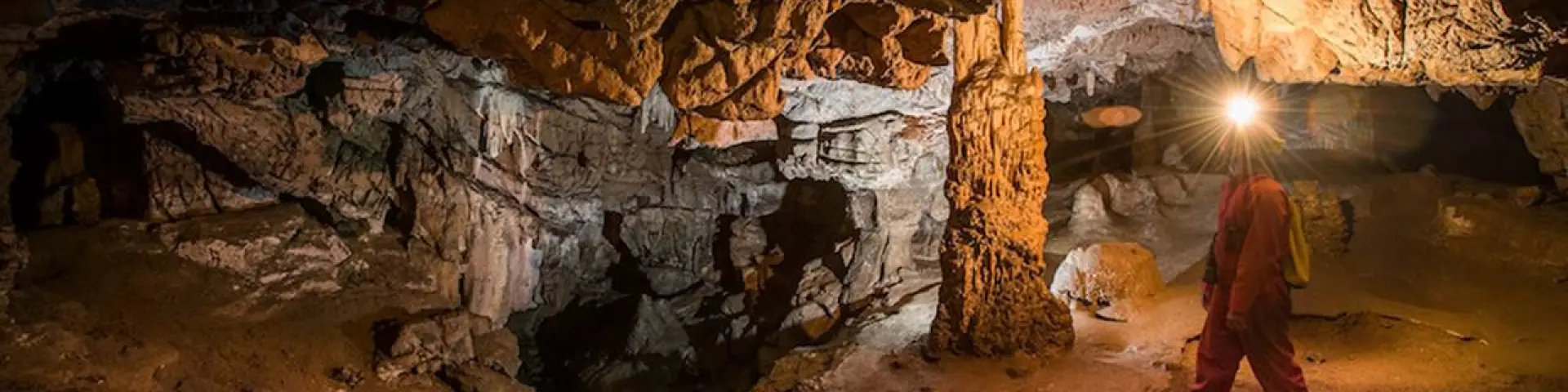 Personne explorant une grotte souterraine avec une lampe frontale
