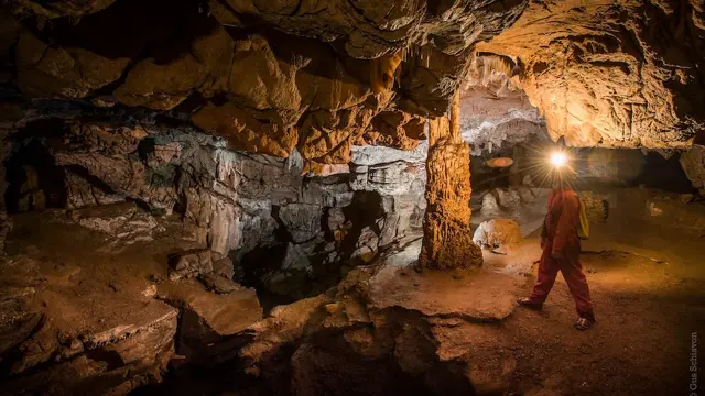 Personne explorant une grotte souterraine avec une lampe frontale