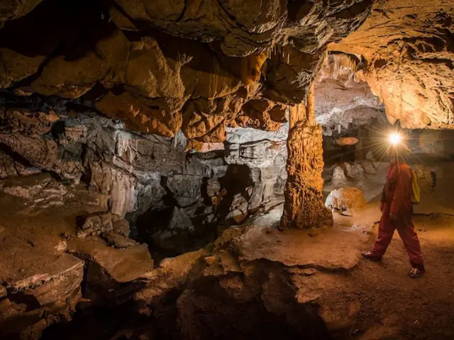 Personne explorant une grotte souterraine avec une lampe frontale