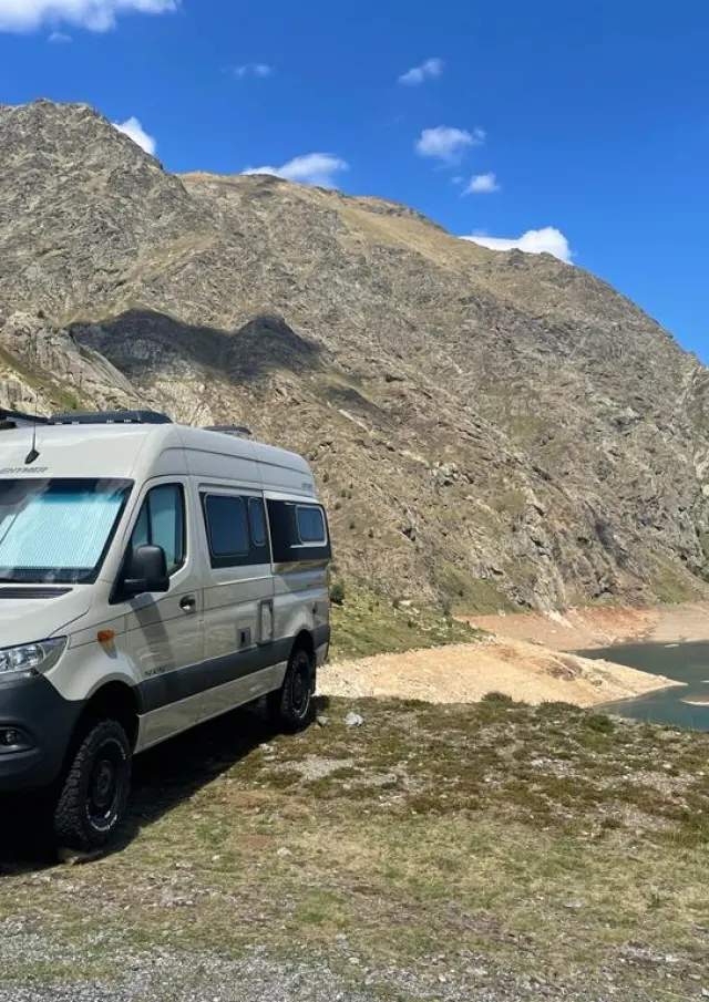 Un van aménagé stationné près d'un lac de montagne