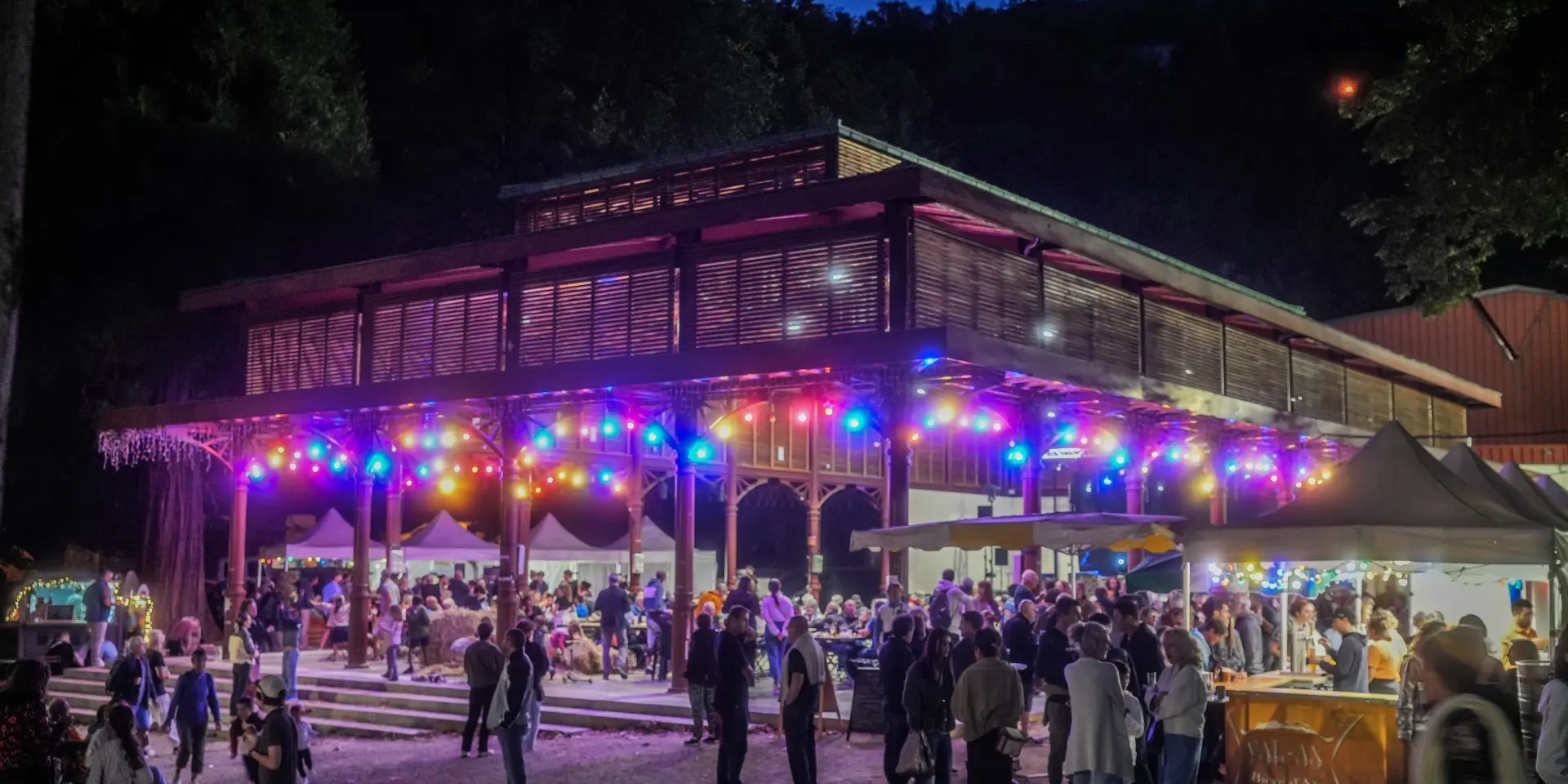 A crowd of people gathered in front of a building decorated with colorful lights