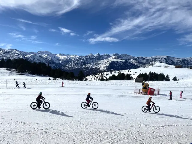 Trois personnes font du vélo sur la neige en montagne