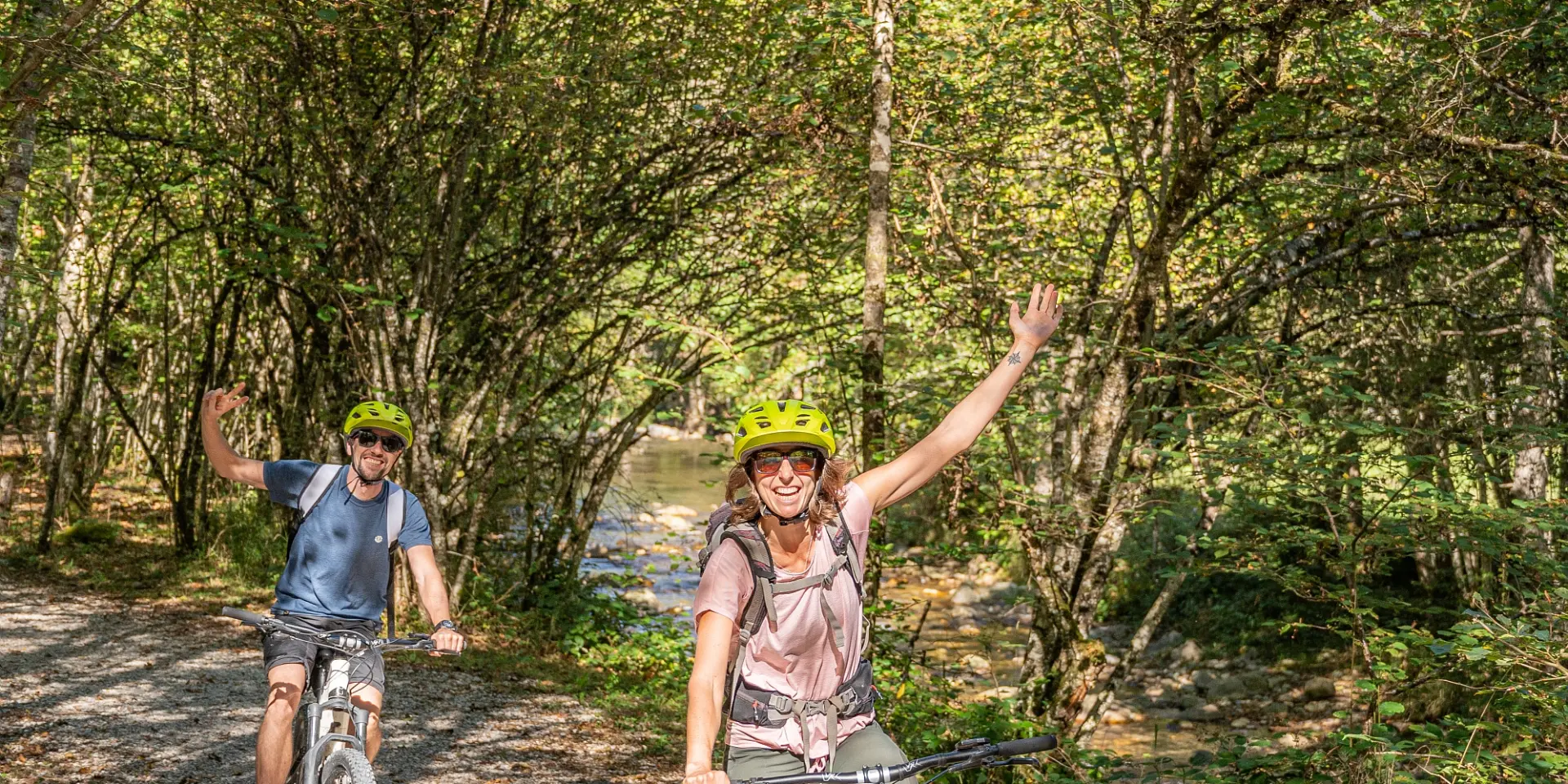 Deux personnes font du vélo sur un chemin de terre en forêt
