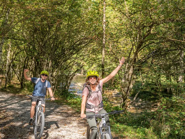 Deux personnes font du vélo sur un chemin de terre en forêt