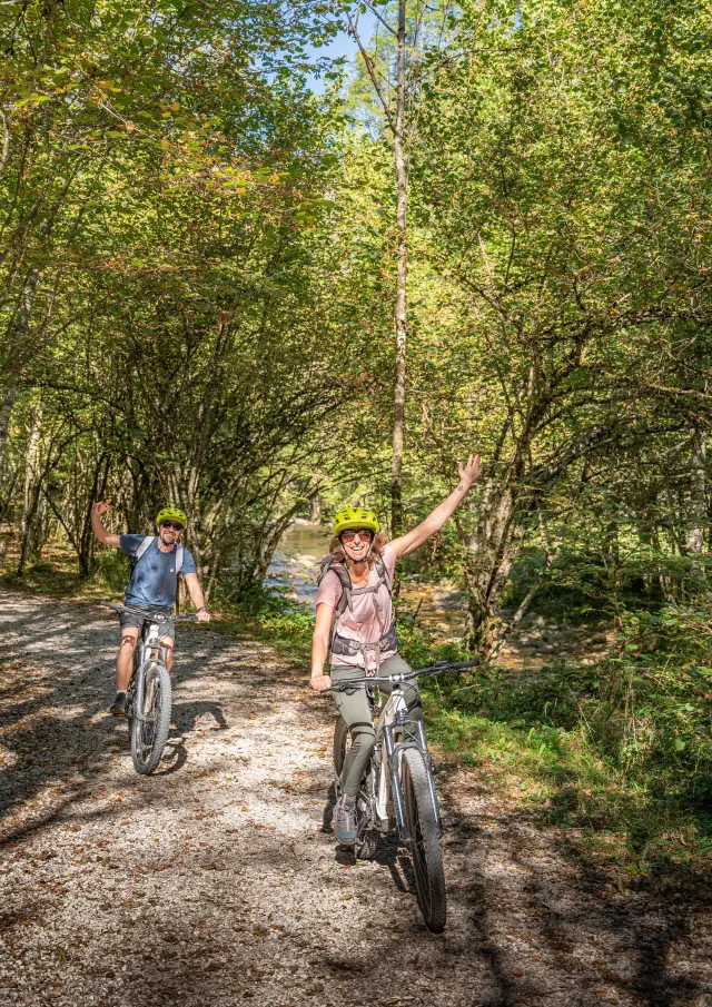 Deux personnes font du vélo sur un chemin de terre en forêt