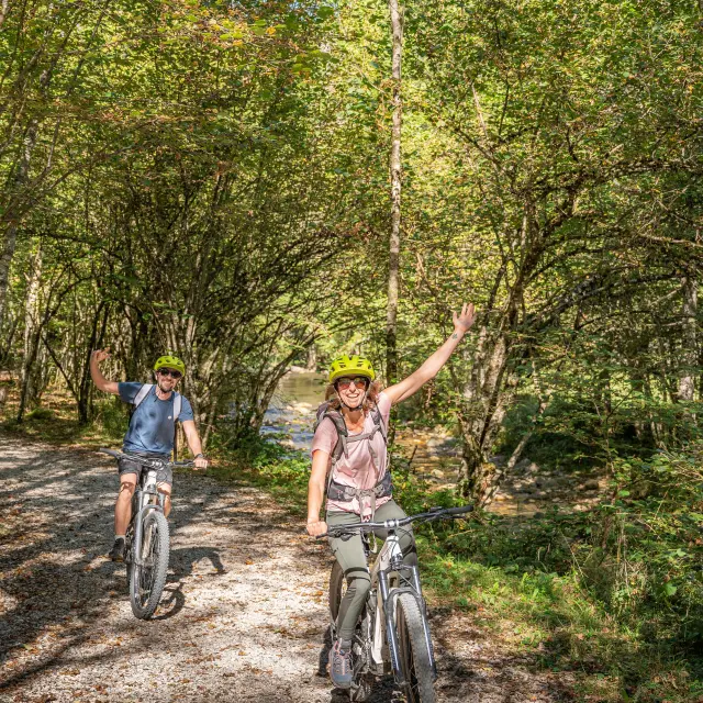 Deux personnes font du vélo sur un chemin de terre en forêt
