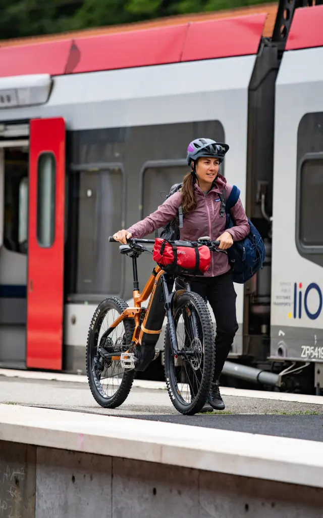 Une femme avec un vélo électrique sur un quai de gare