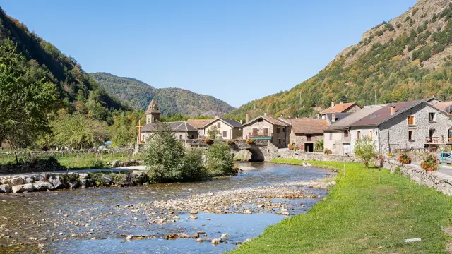 Village avec des maisons en pierre et une église au bord d'une rivière